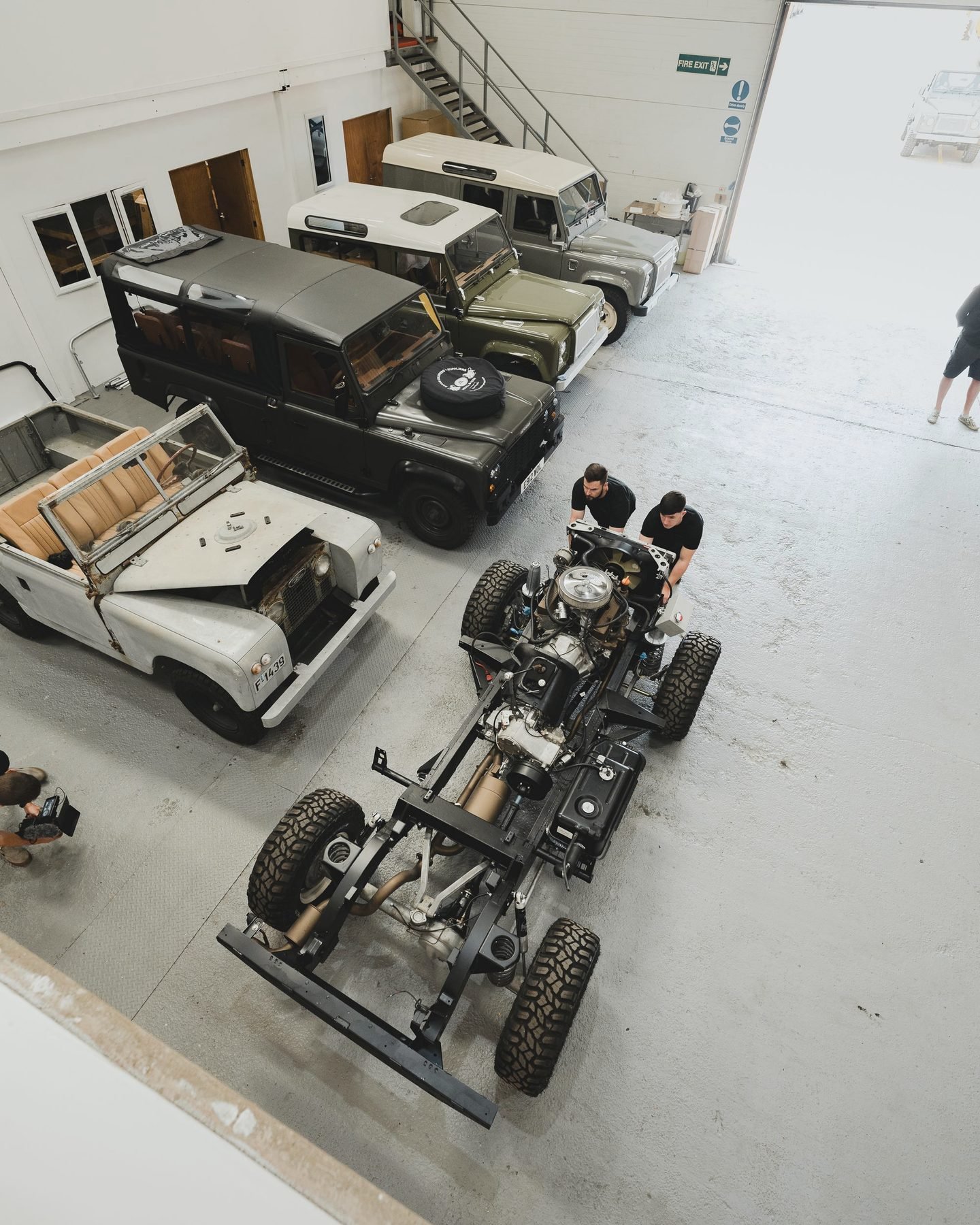 Looking down on a bare vehicle chassis on a workshop floor, body removed