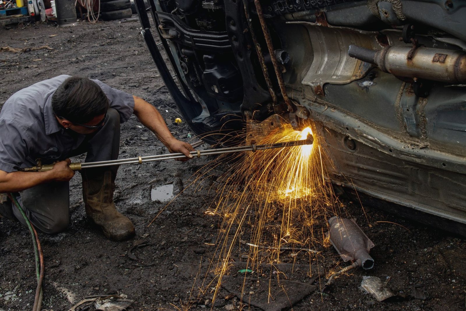 Sparks spraying from a weld under the side of a car on a garage floor
