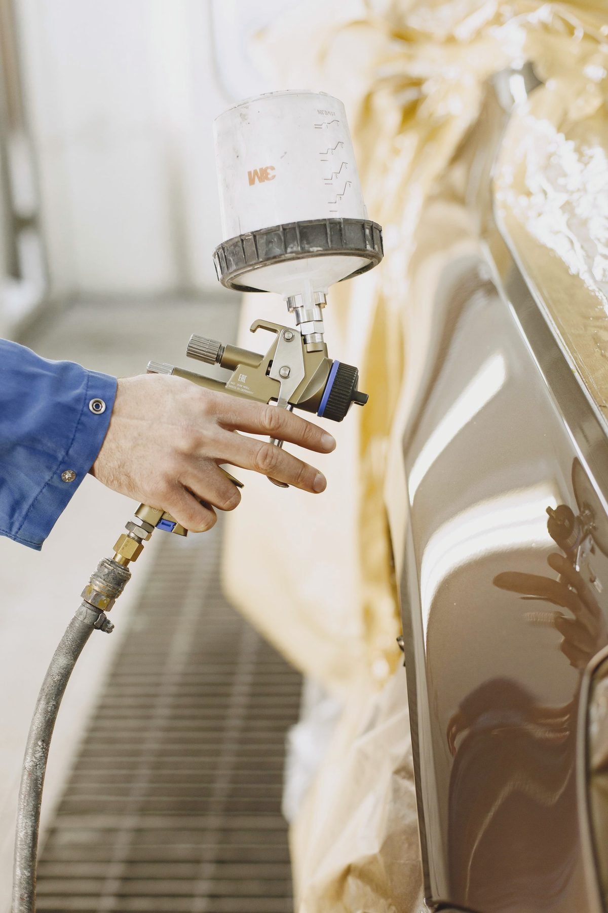 A spray gun laying colour on a car body panel in a booth